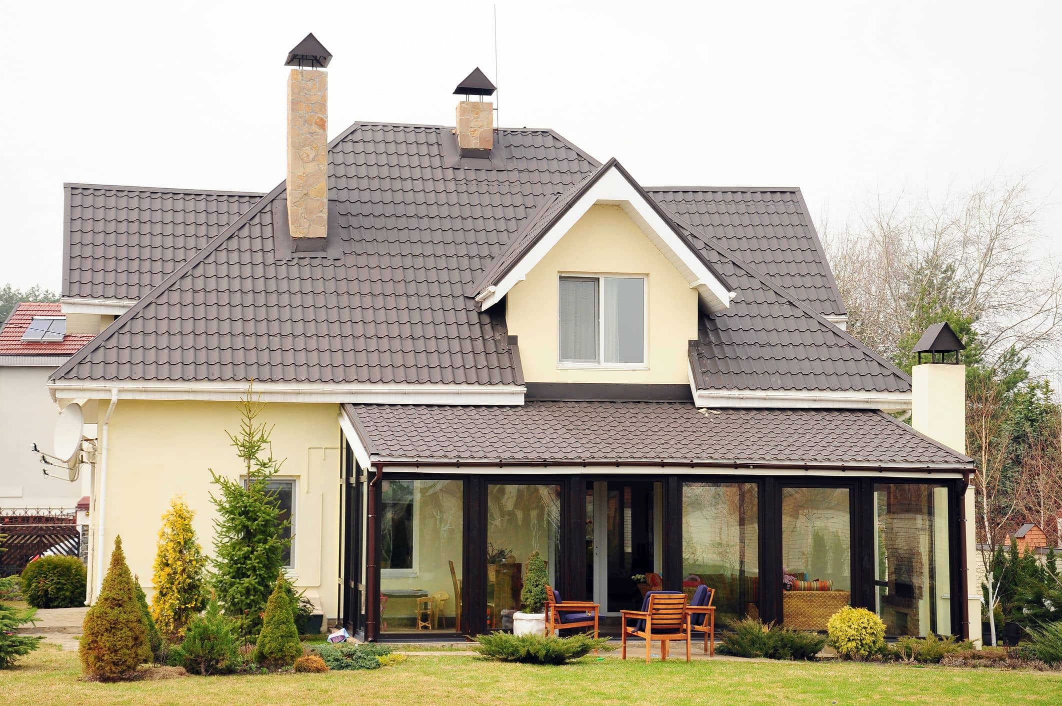 Moderní rodinný dům se žlutou fasádou, velkými okny a prostornou terasou, ideální pro relaxaci.